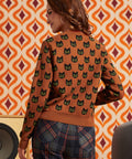 Woman wearing the Old Soul black cat cardigan with plaid pants, showing the repeating cat motif across the back and sleeves