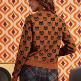 Woman wearing the Old Soul black cat cardigan with plaid pants, showing the repeating cat motif across the back and sleeves