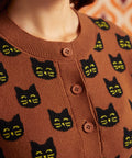 Close-up of the Old Soul cardigan showing black cat faces, crew neckline, ribbed trim, and brown buttons
