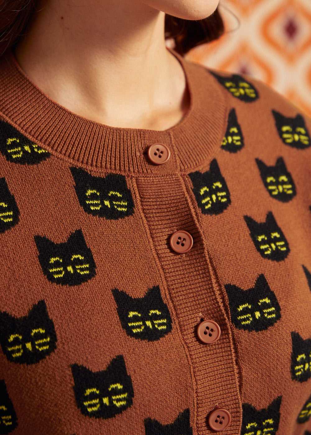 Close-up of the Old Soul cardigan showing black cat faces, crew neckline, ribbed trim, and brown buttons