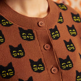 Close-up of the Old Soul cardigan showing black cat faces, crew neckline, ribbed trim, and brown buttons