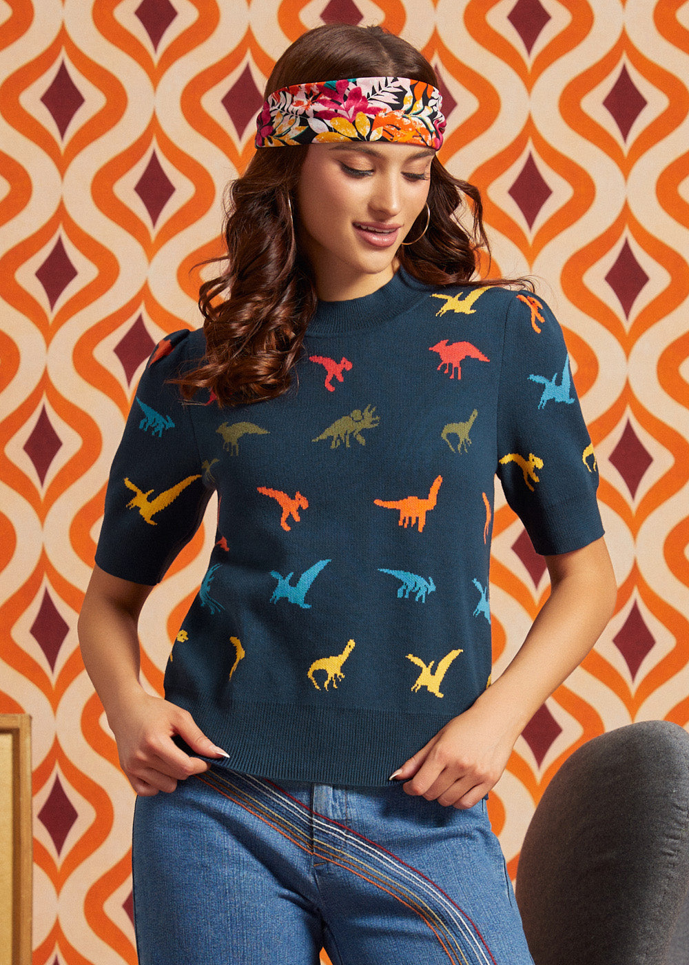 Woman wearing a navy blue 100% cotton short sleeve sweater with colorful dinosaur motif and high-waisted jeans, front view
