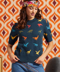 Woman wearing a navy blue 100% cotton short sleeve sweater with colorful dinosaur motif and high-waisted jeans, front view