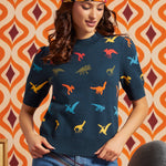Woman wearing a navy blue 100% cotton short sleeve sweater with colorful dinosaur motif and high-waisted jeans, front view