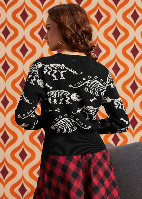 Woman wearing black cardigan with white dinosaur skeleton pattern and red-and-black plaid skirt, back view