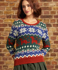 Woman wearing ModCloth's Prehistoric Parade Fair Isle Sweater with colorful dinosaur and snowflake-inspired knit motifs, front view
