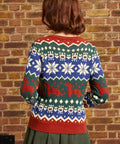 Back view of woman wearing colorful dinosaur Fair Isle sweater with repeating geometric and prehistoric motifs