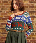 Woman wearing vintage-inspired dinosaur Fair Isle sweater tucked into a high-waisted green skirt