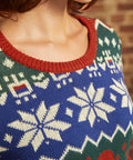 Close-up of 100% cotton dinosaur Fair Isle sweater showing cobalt blue knit, cream motifs, and rust ribbed crew neckline