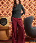 Woman wearing the striped mock neck top tucked into high-waisted burgundy trousers