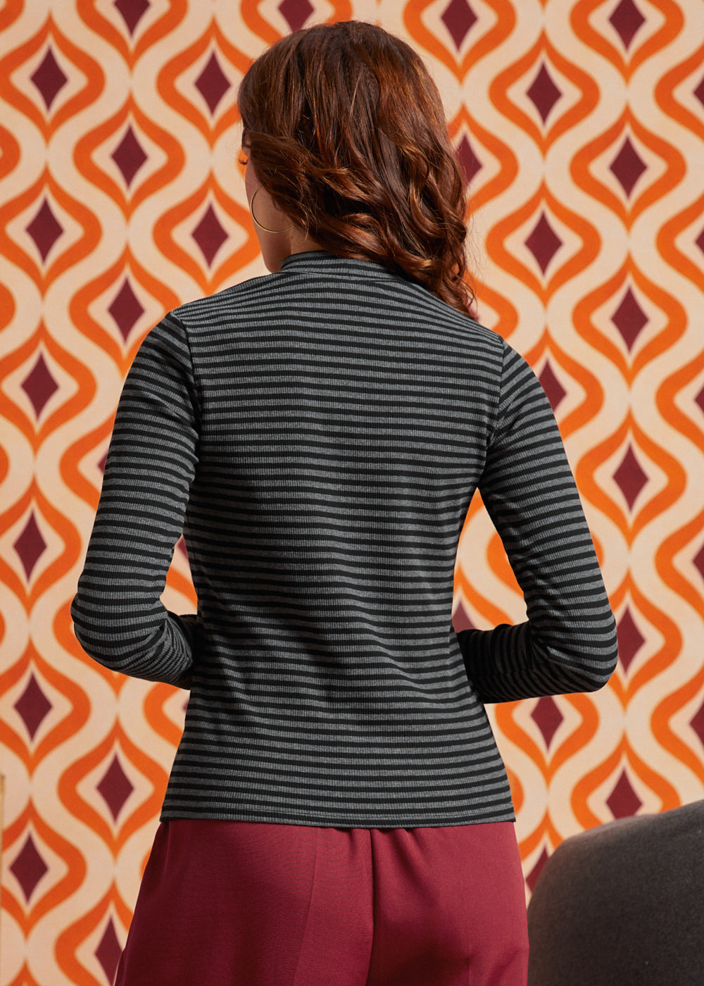 Back view of woman wearing the fitted black and gray striped long sleeve mock neck top