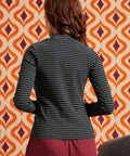 Back view of woman wearing the fitted black and gray striped long sleeve mock neck top