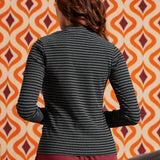 Back view of woman wearing the fitted black and gray striped long sleeve mock neck top