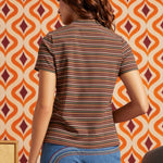 Woman wearing brown striped mock neck short sleeve top with blue jeans, back view showing fitted silhouette and horizontal stripe pattern