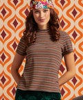 Woman wearing brown striped mock neck short sleeve top in earth tones with floral headscarf, front view