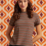 Woman wearing brown striped mock neck short sleeve top in earth tones with floral headscarf, front view
