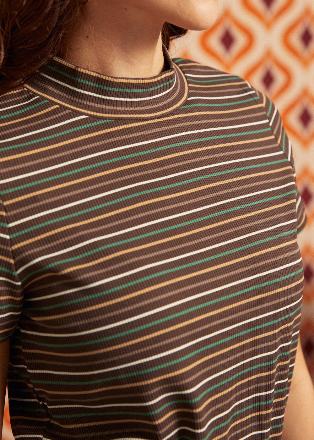 Close-up of brown ribbed mock neck top showing horizontal cream, green, camel, and rust stripes and neckline