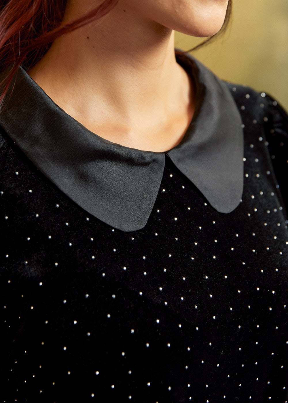 Close-up of a black velvet top showing the smooth Peter Pan collar, and tiny heat-set metallic nailhead studs across the fabric.