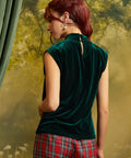 Rear three-quarter view of an emerald green velvet top showing the keyhole back opening with button closure and relaxed silhouette.