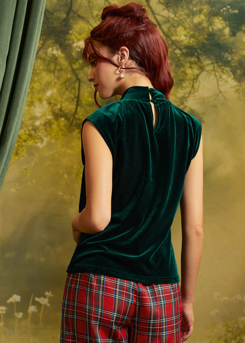 Rear three-quarter view of an emerald green velvet top showing the keyhole back opening with button closure and relaxed silhouette.