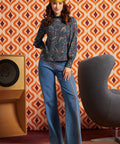 Woman wearing a blue paisley mock neck top with long bishop sleeves and wide-leg jeans, front full-length view