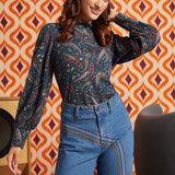 Woman wearing a vintage-inspired paisley mock neck top tucked into high-waisted blue jeans