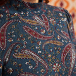 Close-up of blue, burgundy, mustard, and cream paisley print and mock neckline