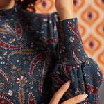 Close-up of blue paisley mock neck top showing gathered bishop sleeve and wide fitted cuff