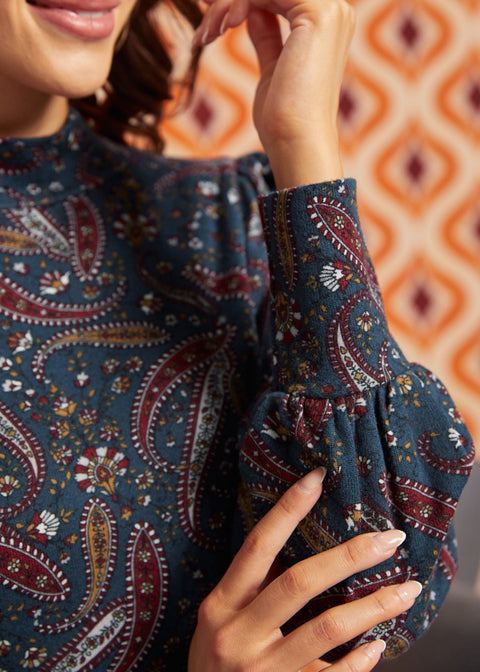 Close-up of blue paisley mock neck top showing gathered bishop sleeve and wide fitted cuff