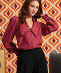 Woman wearing the Petal Picnic raspberry blouse with oversized ruffle collar, long sleeves, and black high-waisted pants.