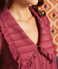Close-up of raspberry blouse showing the oversized pointed collar, ruffled trim, tonal stripes, and button front.