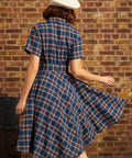 Back view of woman wearing navy plaid belted fit-and-flare dress with short sleeves and full skirt