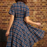 Back view of woman wearing navy plaid belted fit-and-flare dress with short sleeves and full skirt