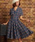 Woman wearing a navy plaid cotton fit-and-flare midi dress with short sleeves, button front, and matching buckle belt