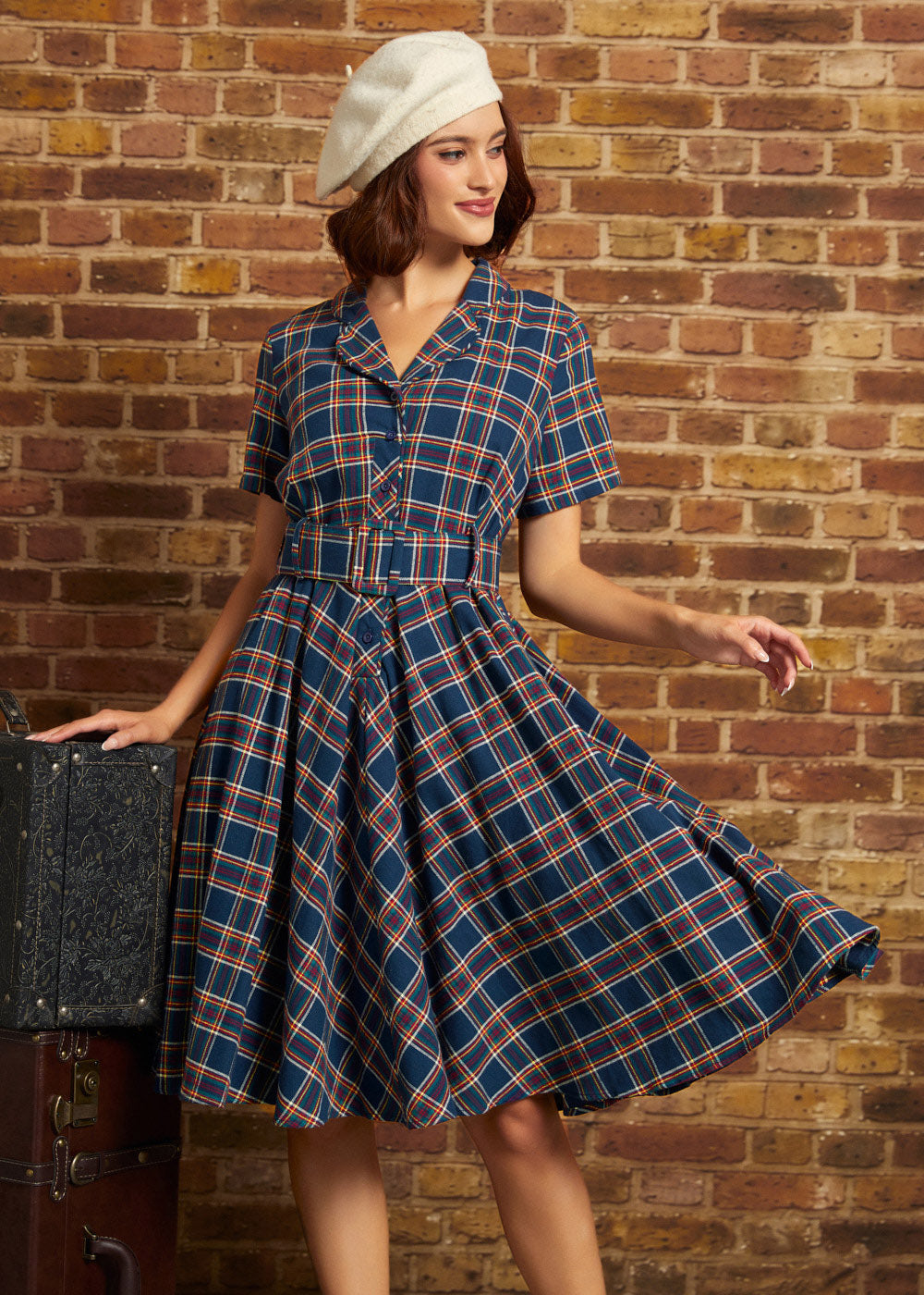 Woman wearing a navy plaid cotton fit-and-flare midi dress with short sleeves, button front, and matching buckle belt
