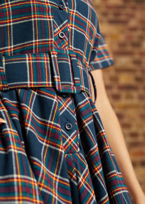 Close-up of plaid shirt dress showing functional button-front bodice, notched collar, and matching belt