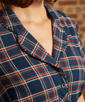 Close-up of plaid shirt dress showing functional button-front bodice, notched collar, and matching belt