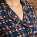 Close-up of plaid shirt dress showing functional button-front bodice, notched collar, and matching belt