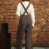 Back view of woman wearing brown plaid cropped pants with suspender straps crossed at the back