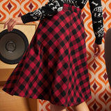 Back view of a woman wearing a red and black buffalo plaid A-line skirt with a zipper