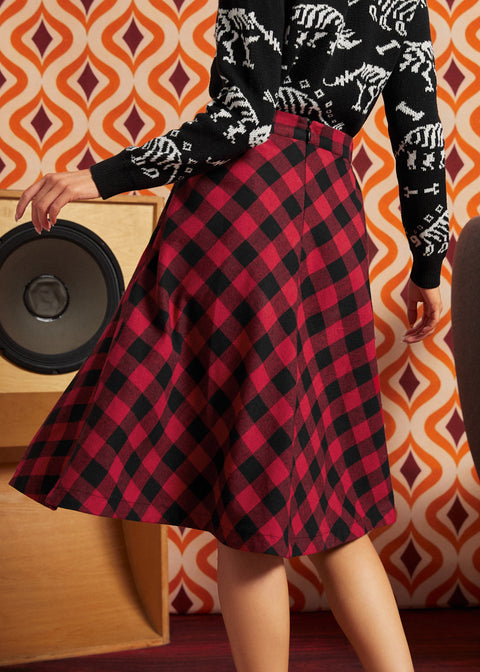 Back view of a woman wearing a red and black buffalo plaid A-line skirt with a zipper