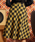 Woman wearing mustard and black check midi skirt with black lace blouse, back view showing full A-line silhouette and center-back zipper