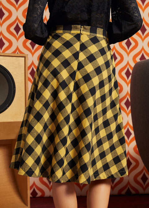 Woman wearing mustard and black check midi skirt with black lace blouse, back view showing full A-line silhouette and center-back zipper