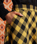 Close-up of mustard and black check cotton skirt showing fitted waistband and side pocket