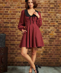 Woman wearing red plaid fit and flare dress with black collar and side pockets, full-length front view