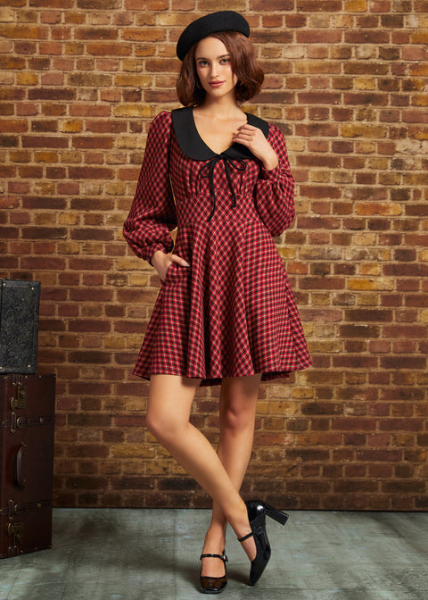 Woman wearing red plaid fit and flare dress with black collar and side pockets, full-length front view