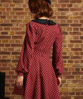 Woman shown from behind wearing red plaid fit and flare dress with long puff sleeves and black collar