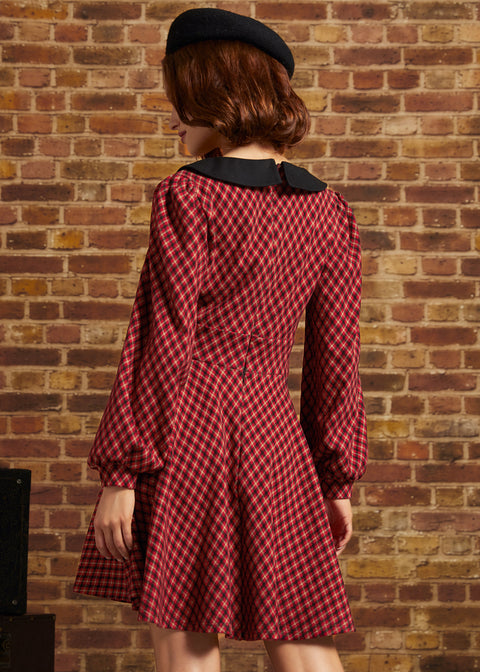 Woman shown from behind wearing red plaid fit and flare dress with long puff sleeves and black collar