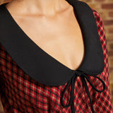 Close-up of oversized black contrast collar and bow tie neckline on red plaid dress