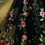 Close-up of a black embroidered skirt with pink and peach flowers and green leaves.